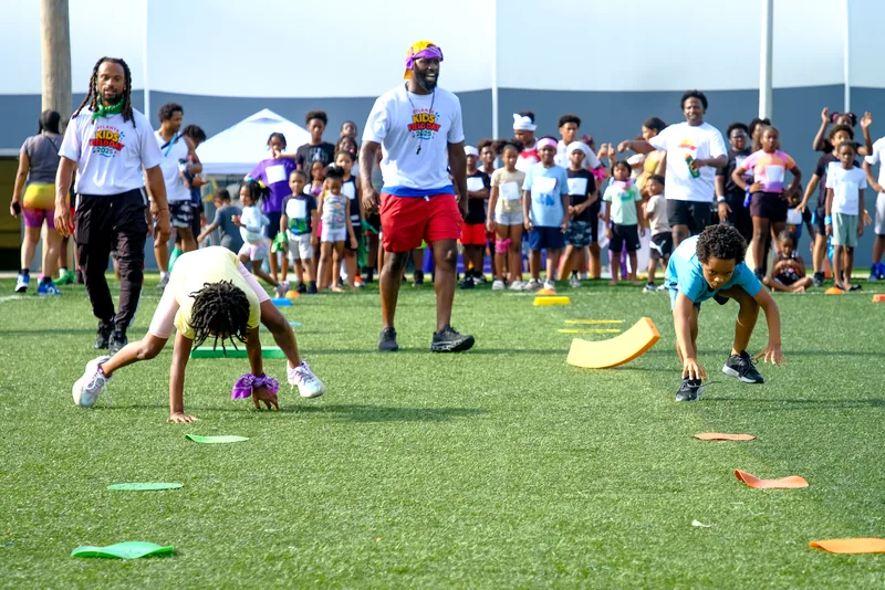 Kids racing through an obstacle course while coaches cheer at a Faith First Fitness field day