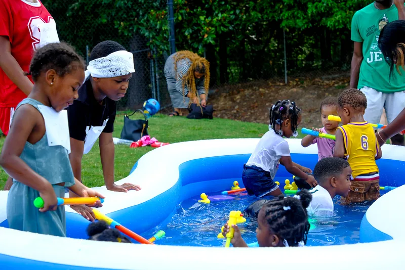 Kids playing with water toys in an inflatable pool at an outdoor event